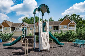 a playground with a slide and climbing equipment in front of a row of houses